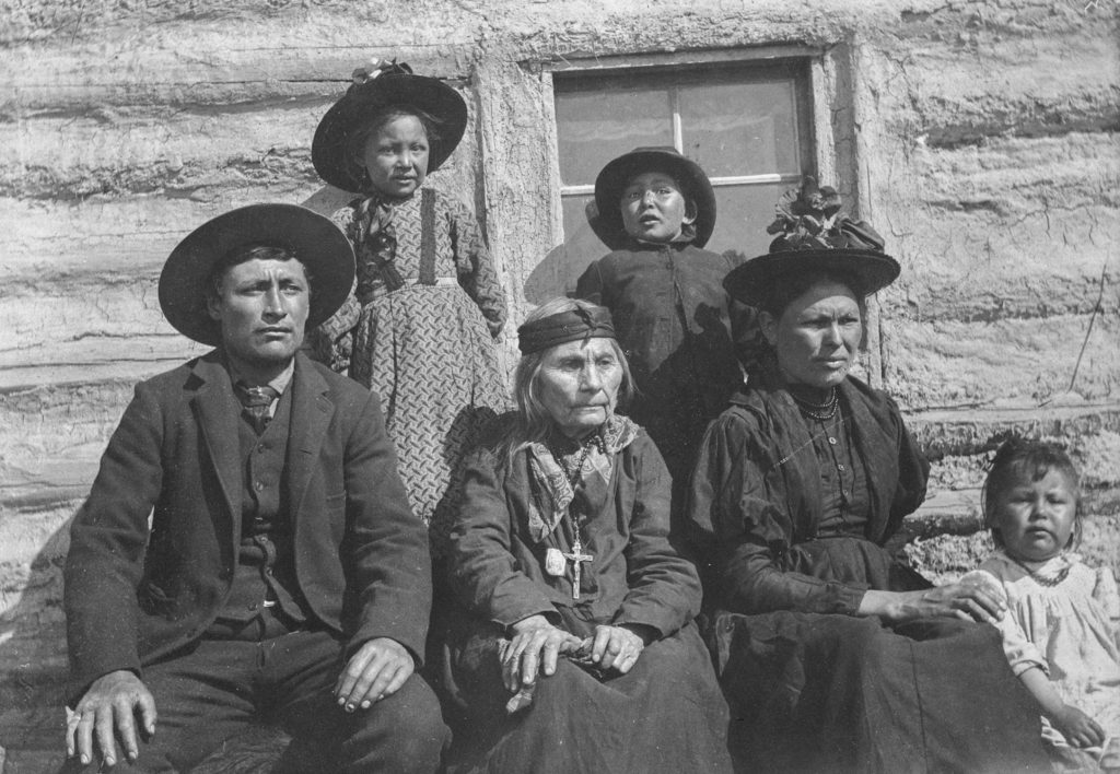 Métis family sitting next to building