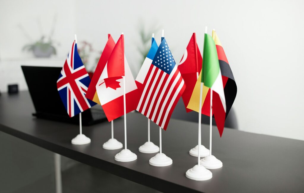 Many Different Countries Flags And Laptop Standing On Office Table